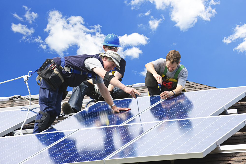 Tre håndværkere installerer solceller på tag